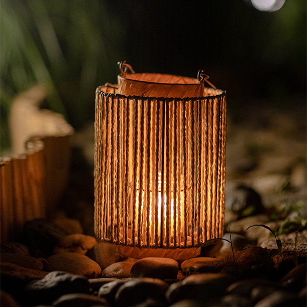 collapsible camping candle lantern burning in darkness on a rustic