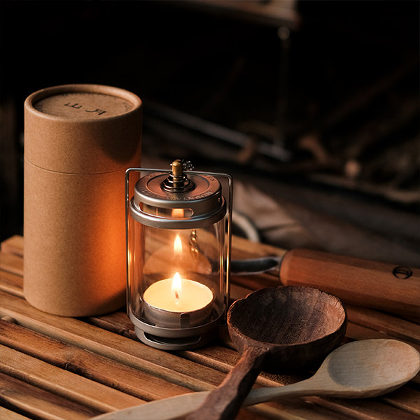 collapsible camping candle lantern burning in darkness on a rustic
